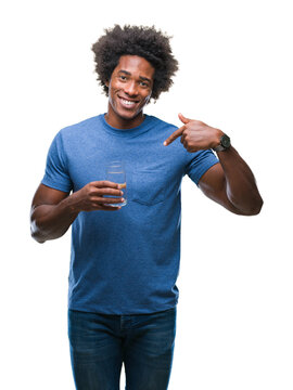 Afro american man drinking glass of water over isolated background with surprise face pointing finger to himself