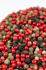 A mixture of different peppercorns on a white background