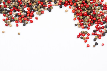 Obraz premium Red, green, white and black peppercorns on a white background, copy space for text
