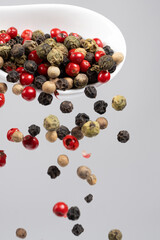 Different types of peppercorns pouring. Red, green, white and black pepper.