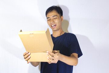 Asian teenage boy in navy blue shirt is looking at the opened box with a sweet smile on his face