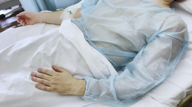 Intravenous morphine infusion for suffering patient lying on hospital bed in disposable surgical gown, medical treatment for patient losing hope in future, support of patient approaching to death