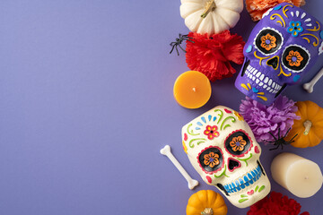 Vibrant Mexican Day of the Dead arrangement with painted sugar skulls, flowers, and candles on a purple background showcasing traditional festive elements