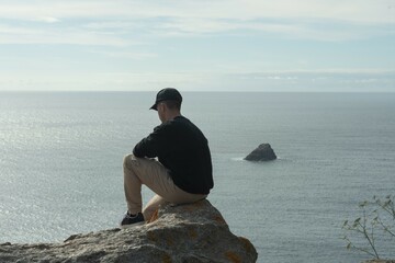 Guy sitting on a rock looking at the sea