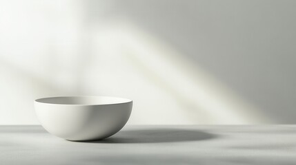 Fototapeta premium A simple white bowl on a light surface, casting a soft shadow in a minimalistic setting.