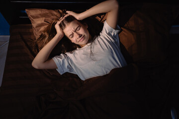 Waking up with a headache. Teen girl can't asleep restless on bed, having bad sleep troubles with...