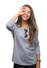 Young beautiful arab woman wearing sunglasses over isolated background doing ok gesture with hand smiling, eye looking through fingers with happy face.