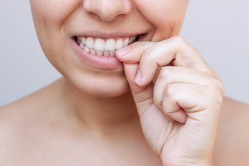 Cropped shot of a young nervous caucasian woman biting her nails because of stress, anxiety, uncertainty isolated on a light grey background. Bad habit. The girl biting off a burr