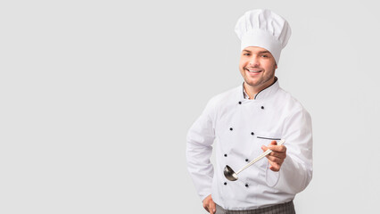 Cheerful Chef Cook Man Holding Ladle Soup Spoon Smiling At Camera Standing Over White Studio Background. Panorama