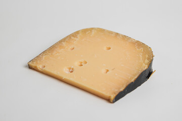 photographie d'un morceau de gouda vieux, un fromage hollandais, sur un fond blanc.