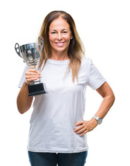 Middle age hispanic winner woman celebrating award holding trophy over isolated background with a happy face standing and smiling with a confident smile showing teeth
