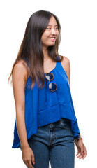 Fototapeta premium Young asian woman over isolated background looking away to side with smile on face, natural expression. Laughing confident.