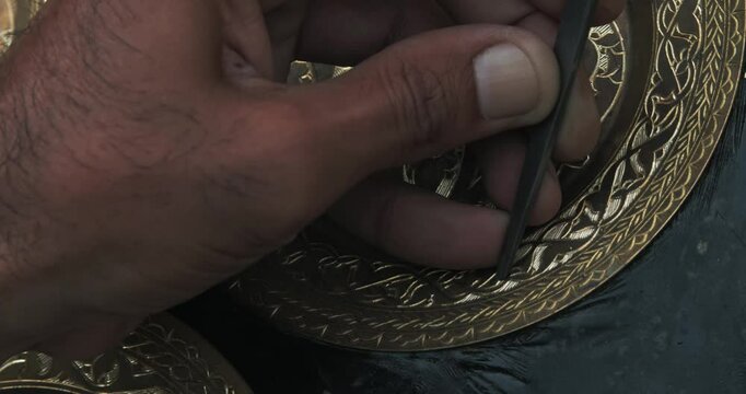 A master embosser creates a pattern on a copper plate using ancient technologies.
