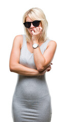 Young beautiful blonde woman wearing sunglasses over isolated background looking stressed and nervous with hands on mouth biting nails. Anxiety problem.