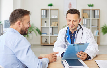 Doctor or nurse discusses test results and offers advice to a patient during a hospital clinic...
