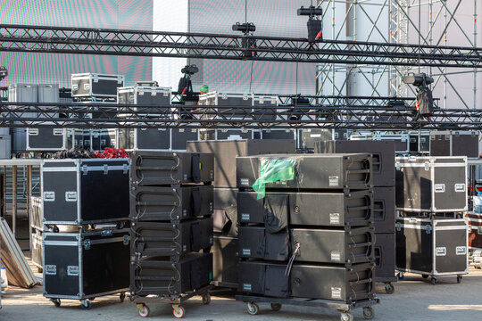 A large area is filled with stacked equipment cases and staging gear, being prepared for an upcoming event.
