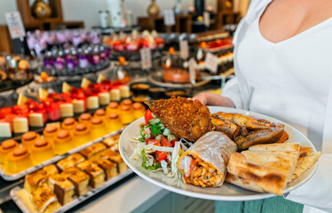 Woman holding a plate full of food. All inclusive concept.