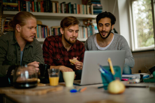 Three friends eating breakfast and watching something on a laptop - Powered by Adobe
