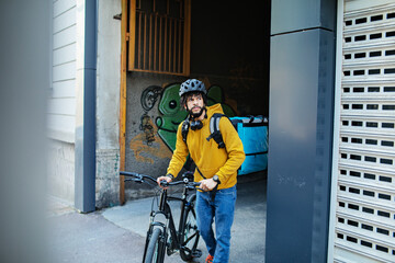 Delivery man biking through city street with a backpack