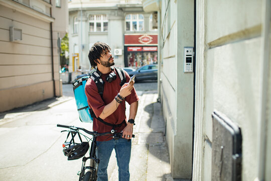 Food delivery man checking address on smartphone