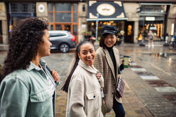 Three diverse female friends walking together on city street