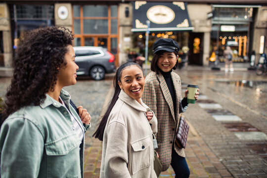 Three diverse female friends walking together on city street - Powered by Adobe