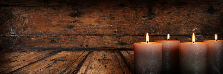 Vier brennende Advents candles on weathered old wood. Horizontal symbol background with warm glow...
