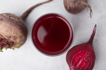 Fresh beet juice in glass and ripe vegetables on gray table, flat lay