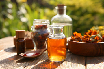 Different tinctures and ingredients on wooden table outdoors