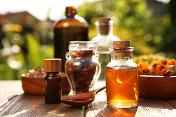 Different tinctures and ingredients on wooden table outdoors