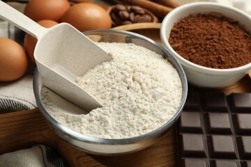 Flour and scoop in bowl, cocoa and chocolate for making dough on table, closeup