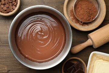 Chocolate dough in bowl and ingredients on wooden table, flat lay