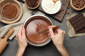 Woman making chocolate dough at grey table, top view