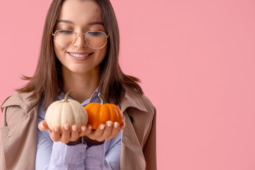 Beautiful young woman with pumpkins on pink background, closeup