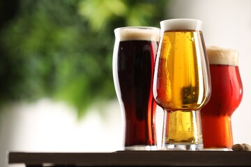 Glasses with different types of beer on table against blurred background, closeup. Space for text