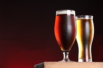 Glasses with different types of beer on board against dark background, closeup. Space for text