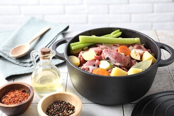 Cooking stew. Uncooked meat and vegetables in pot on white tiled table