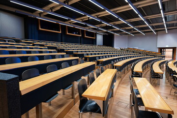 Empty college or university classroom or lecture hall. Wooden desks and benches, no people