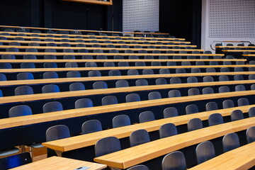 Empty college or university classroom or lecture hall. Wooden desks and benches, no people