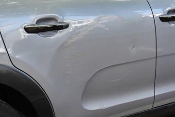 Lightly scratched, scraped and dented car door panel. Close up shot, no people