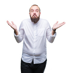 Naklejka premium Young caucasian hipster man over isolated background clueless and confused expression with arms and hands raised. Doubt concept.