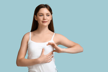 Young woman checking her breast  on blue background