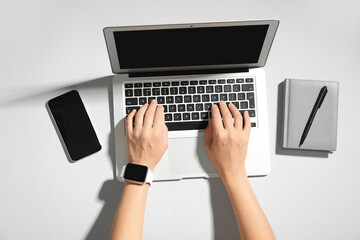 Female hands with laptop, notebook and mobile phone on grey background