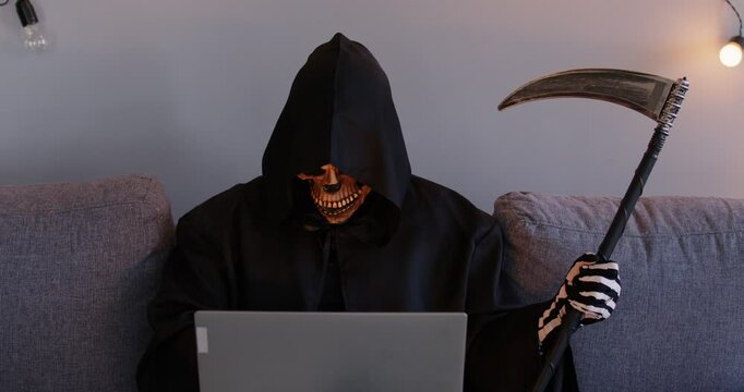Scary dangerous hacker Halloween Grim Reaper horrific figure masked secret man with laptop online, financial criminal of digital wallet fraud, disaster, fake investment manager, alert platform
