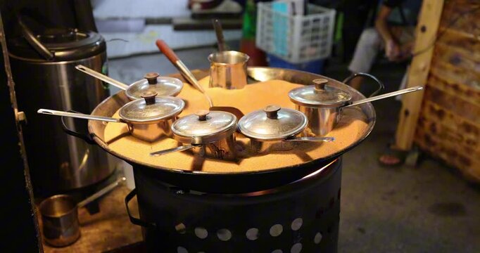 Coffee ban pot roasting on in a pan full of sand on flame at roadside caf&eacute;