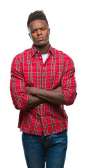 Young african american man over isolated background skeptic and nervous, disapproving expression on face with crossed arms. Negative person.