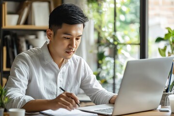 Focused Remote Leadership A young Asian businessman conducts a virtual meeting from his home, demonstrating leadership and strategic thinking in a remote setting.