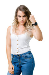 Fototapeta premium Young beautiful blonde woman over isolated background angry and mad raising fist frustrated and furious while shouting with anger. Rage and aggressive concept.