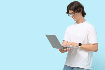 Male programmer in eyeglasses with laptop on blue background