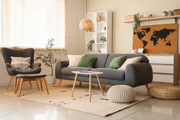 Interior of living room with armchair, sofa and world map on beige wall